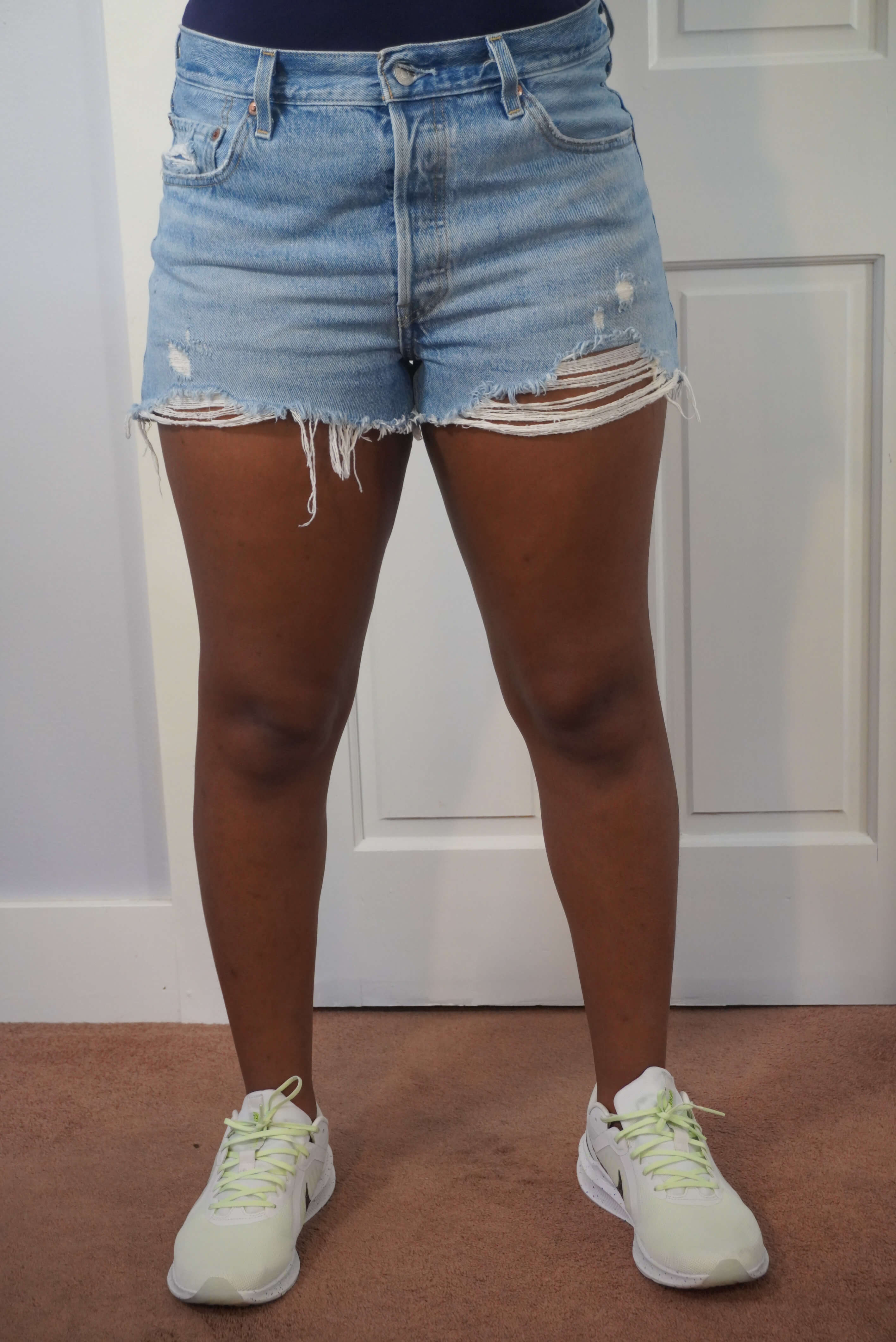 This image shows the front view of a pair of 501 Levi's shorts on the author. These shorts have frayed bottoms and a stone wash look to it.