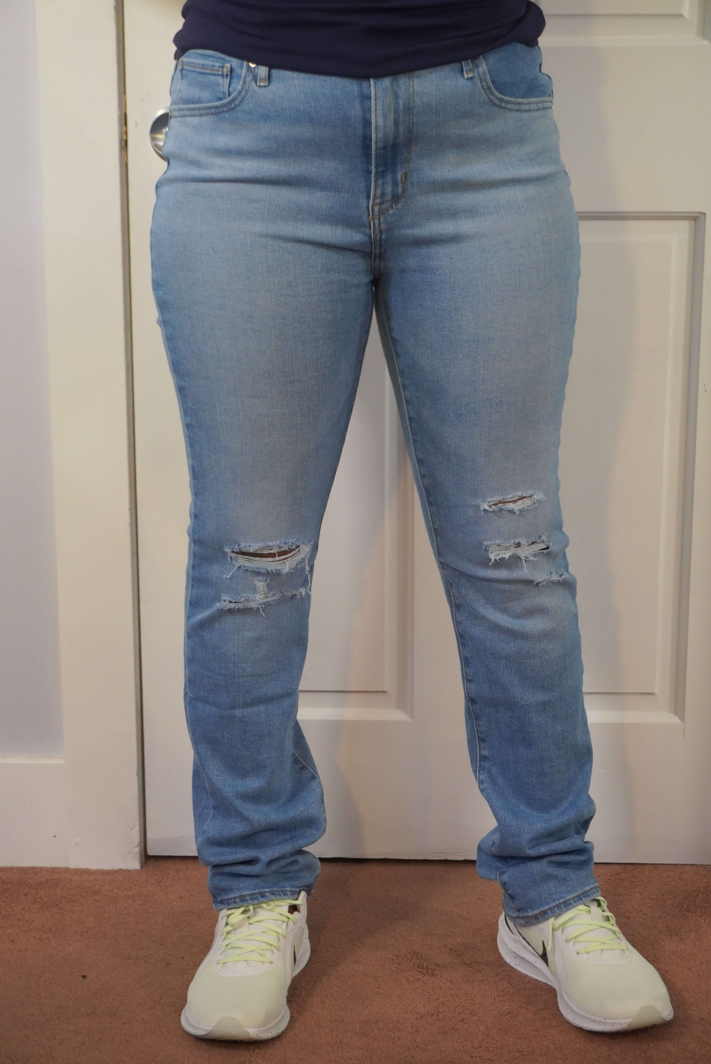 This image shows a front view of the Levi's 724 jeans in a light blue stone wash. The jeans are distressed at the knee area.