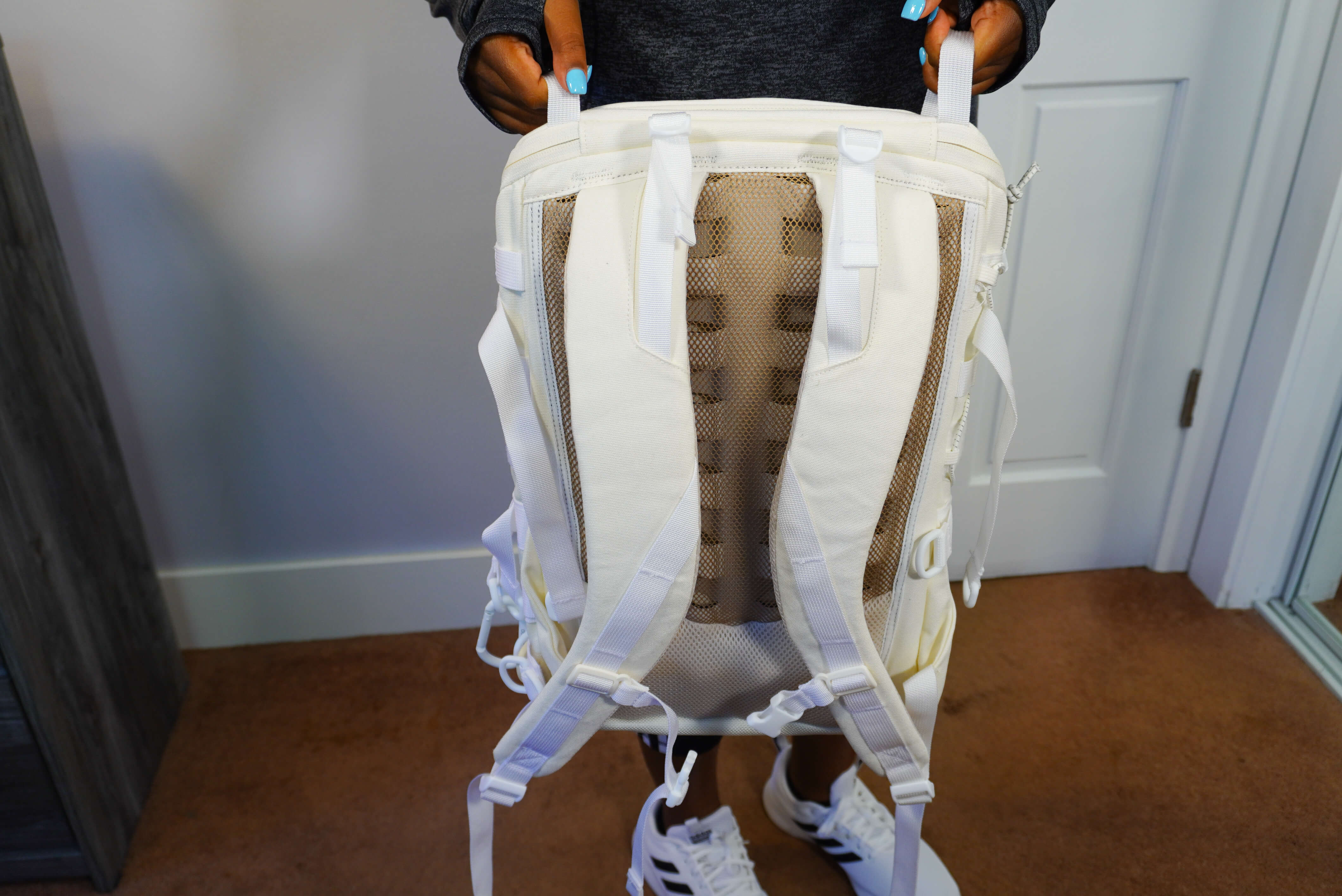 Image of me holding the backpack to show the shoulder straps and mesh netting on the back.