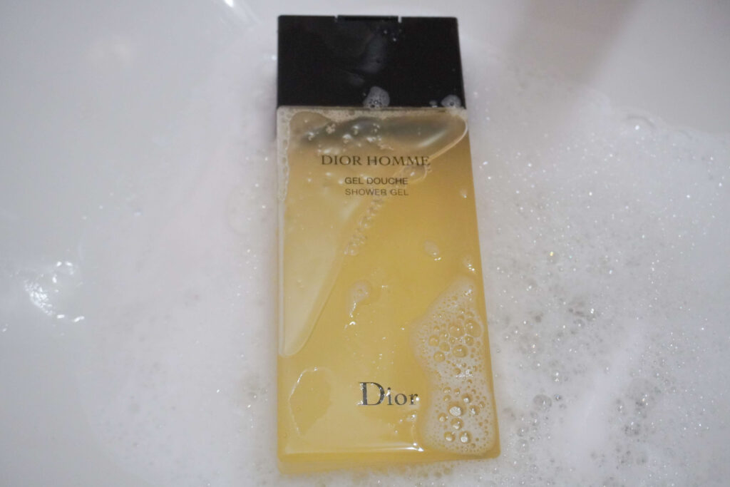 Image displays bottle of Dior Homme laying down in bath suds