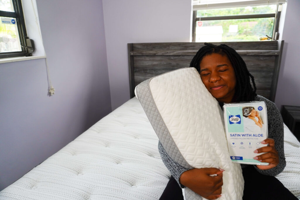 Image of me holding the memory foam pillow in my right hand and holding the satin aloe pillow protector in my left.