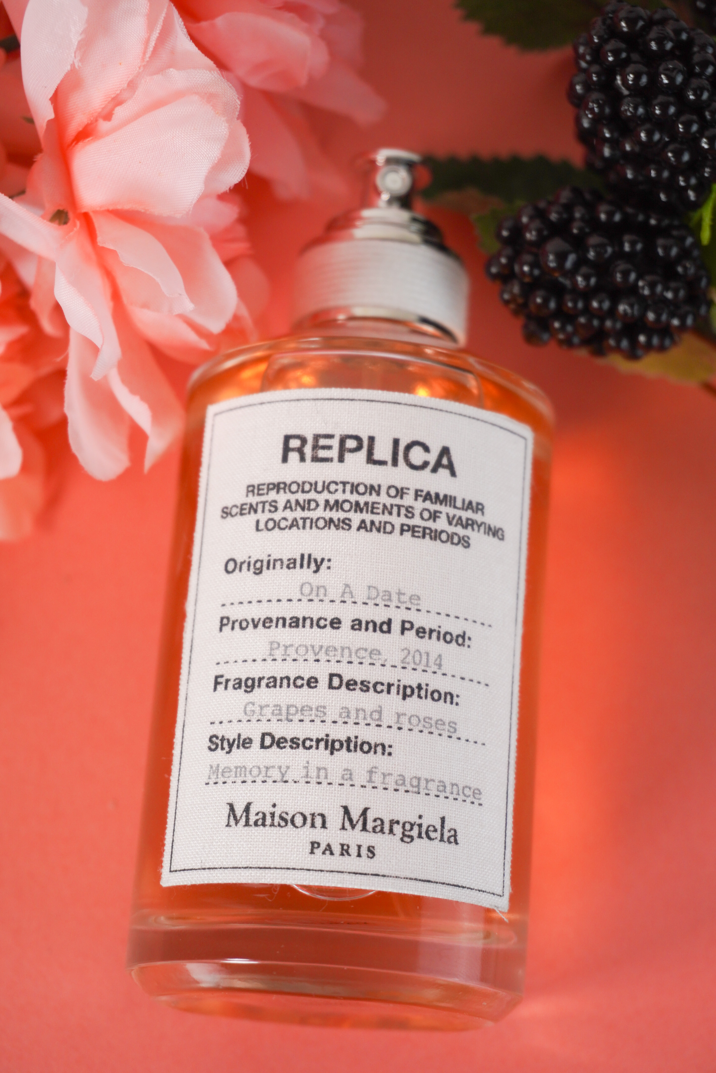Image of the Masion Margiela fragrance face up with a pink flower on the left and blackberries on the right.