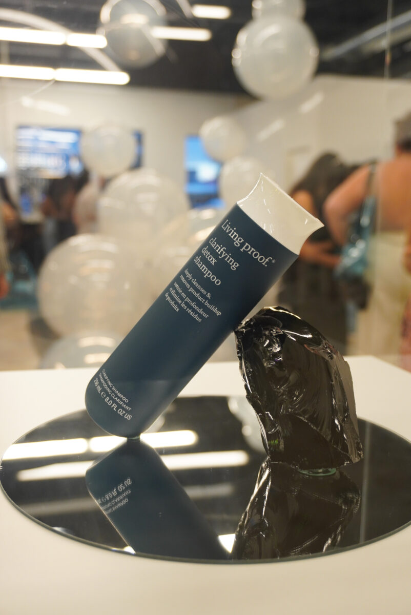 Image of the Living Proof® Detox Shampoo against a charcoal prop.
