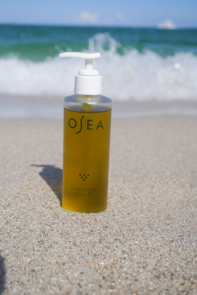 Image of the OSEA Undaria Body Oil on the beach.